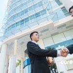 two men shaking hands outside an office building