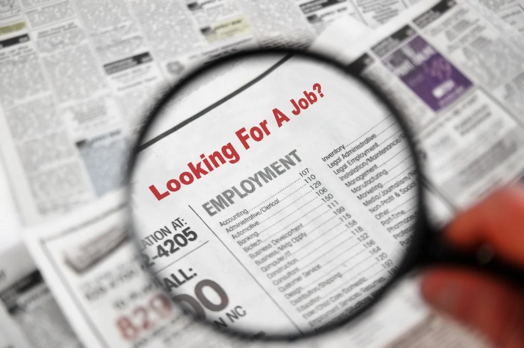 jobseeker searching job listings in printed newspaper