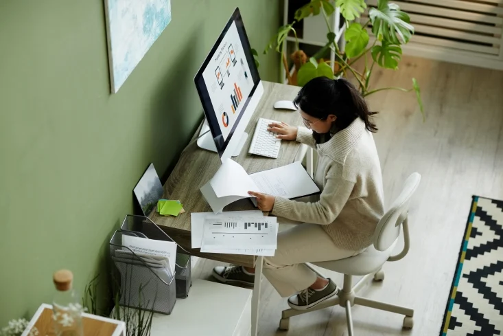 UI/UX design skills article visual - High angle portrait of young woman using computer at home office and working with data, copy space