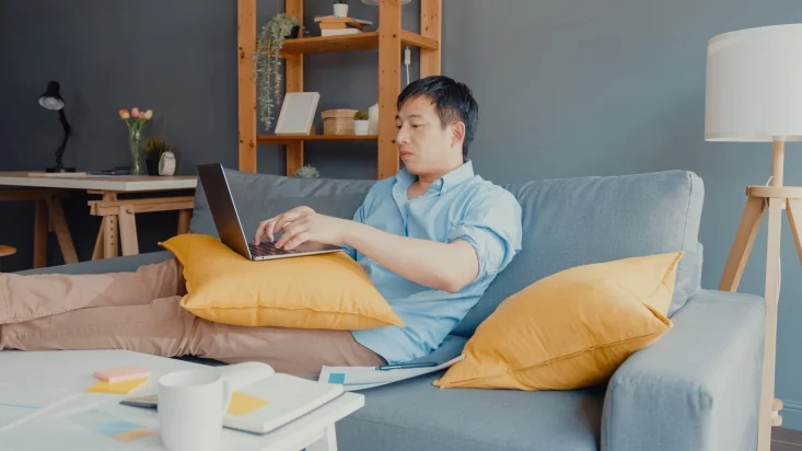 a man working from his couch on a laptop