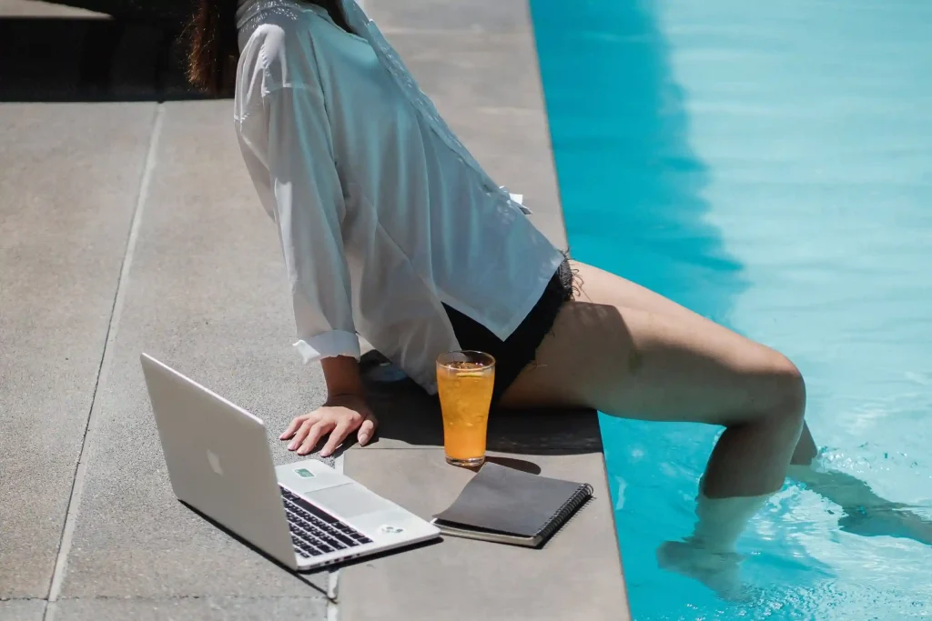 woman dipping legs in a pool while working