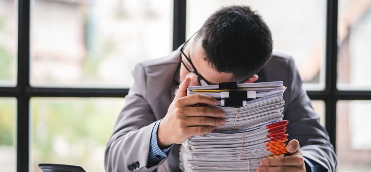 Man resting head over pile of documents