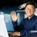 man waving at screen while looking at laptop