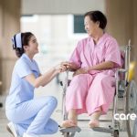 a nurse kneeling down next to an elderly woman in a wheelchair