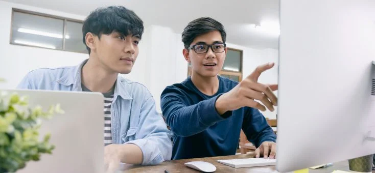 2 male workers discussing over something on the computer screens, AI adoption workforce sentiment, artificial intelligence