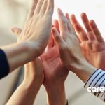 Close-up of a group of diverse hands stacked together, symbolizing teamwork and collaboration, with a soft focus background