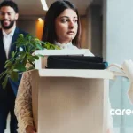 Asian woman experiencing retrenchment and job loss carrying box of things out of office